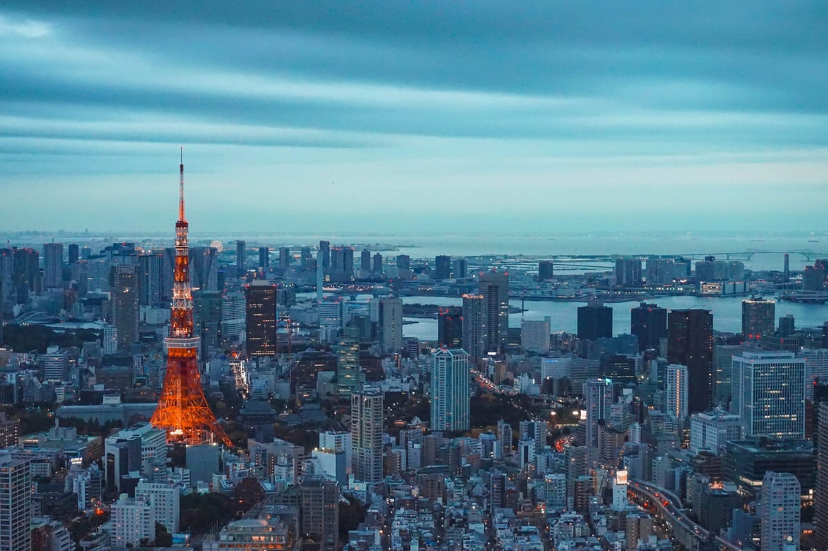 Grey and blue Tokyo cityscape. Red Tokyo tower stands tall on the left.