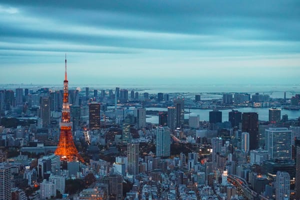 Grey and blue Tokyo cityscape. Red Tokyo tower stands tall on the left.